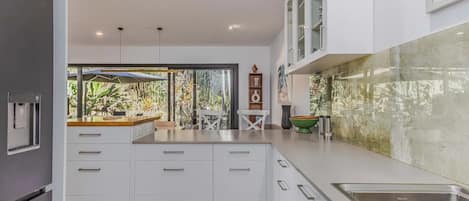 A modern kitchen with white cabinetry, a built-in sink, and a view of the outdoors.