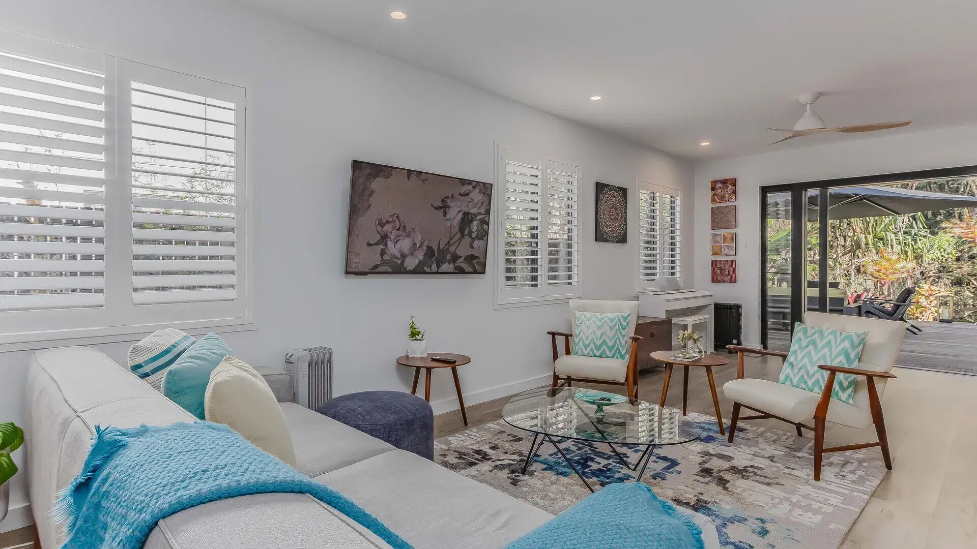 A modern living room with a sofa, armchairs, a coffee table, and a large window with blinds.