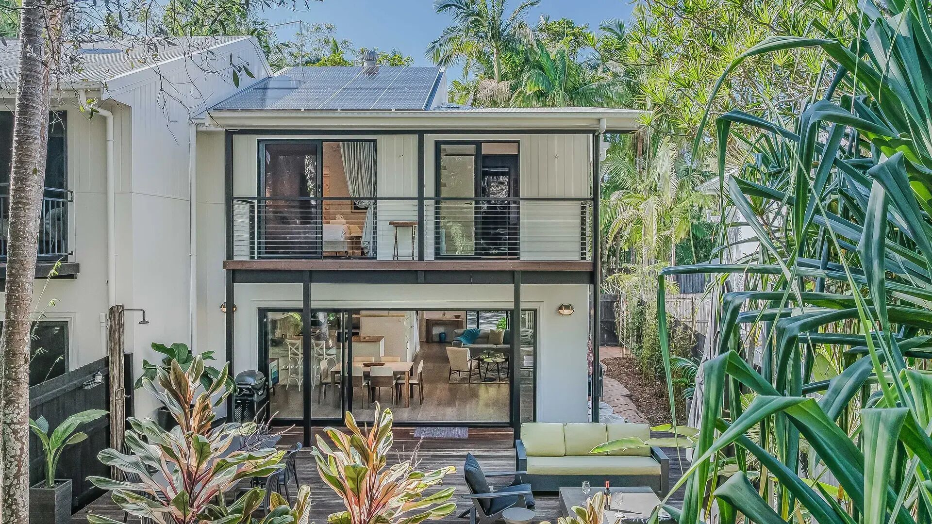 Una casa de dos pisos con un balcón, un comedor y una cocina visible.