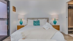 A hotel room with a bed, two nightstands, a window, and a door. - Samsara in Suffolk Park (Suffolk Park)