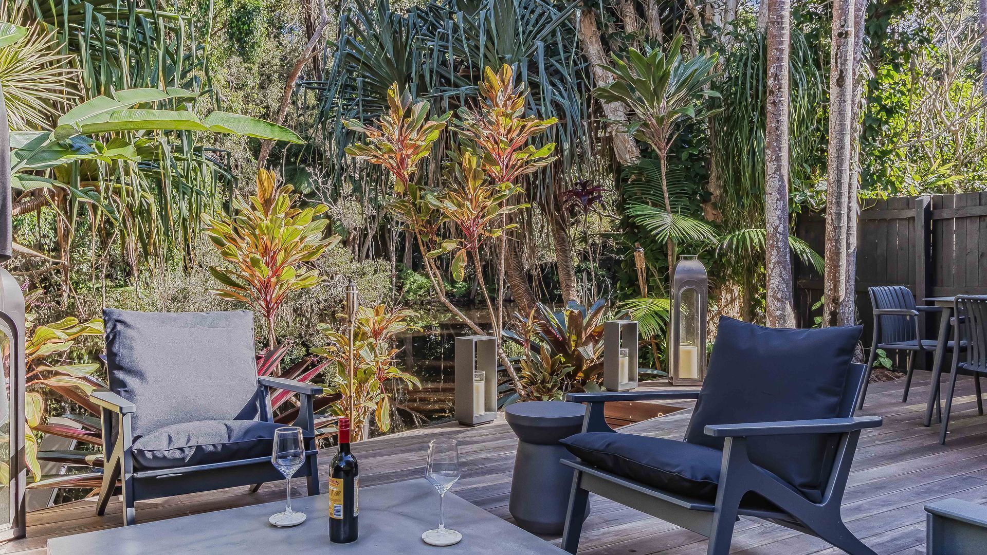 An outdoor seating area with modern furniture, surrounded by lush tropical plants.