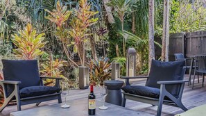 An outdoor seating area with two chairs, a table, and a bottle of wine. - Samsara in Suffolk Park (Suffolk Park)