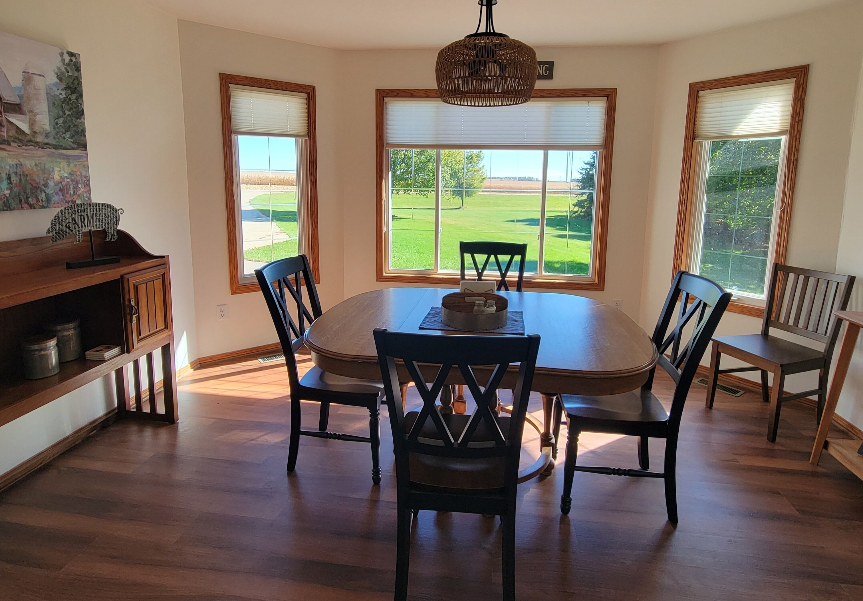 A dining room with a round table, four chairs, and a chandelier.