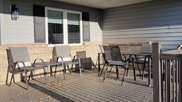 A covered patio with outdoor furniture, a brick wall, and a window with shutters.