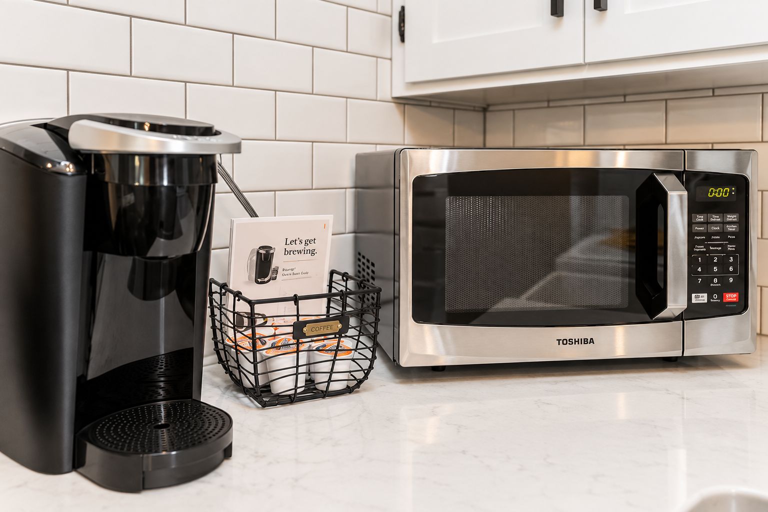 A kitchen with a coffee maker, a microwave, and a basket of coffee pods.