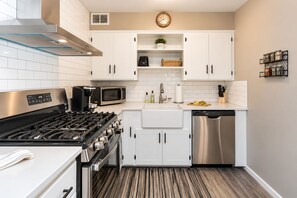 A modern kitchen with white cabinets, stainless steel appliances, and a wooden floor. - Immaculate Farmhouse, Quiet, Safe, NewBo Market (Cedar Rapids)