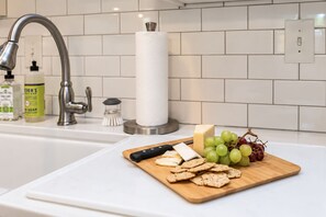 A kitchen counter with a cutting board holding cheese, crackers, and grapes. - Immaculate Farmhouse, Quiet, Safe, NewBo Market (Cedar Rapids)