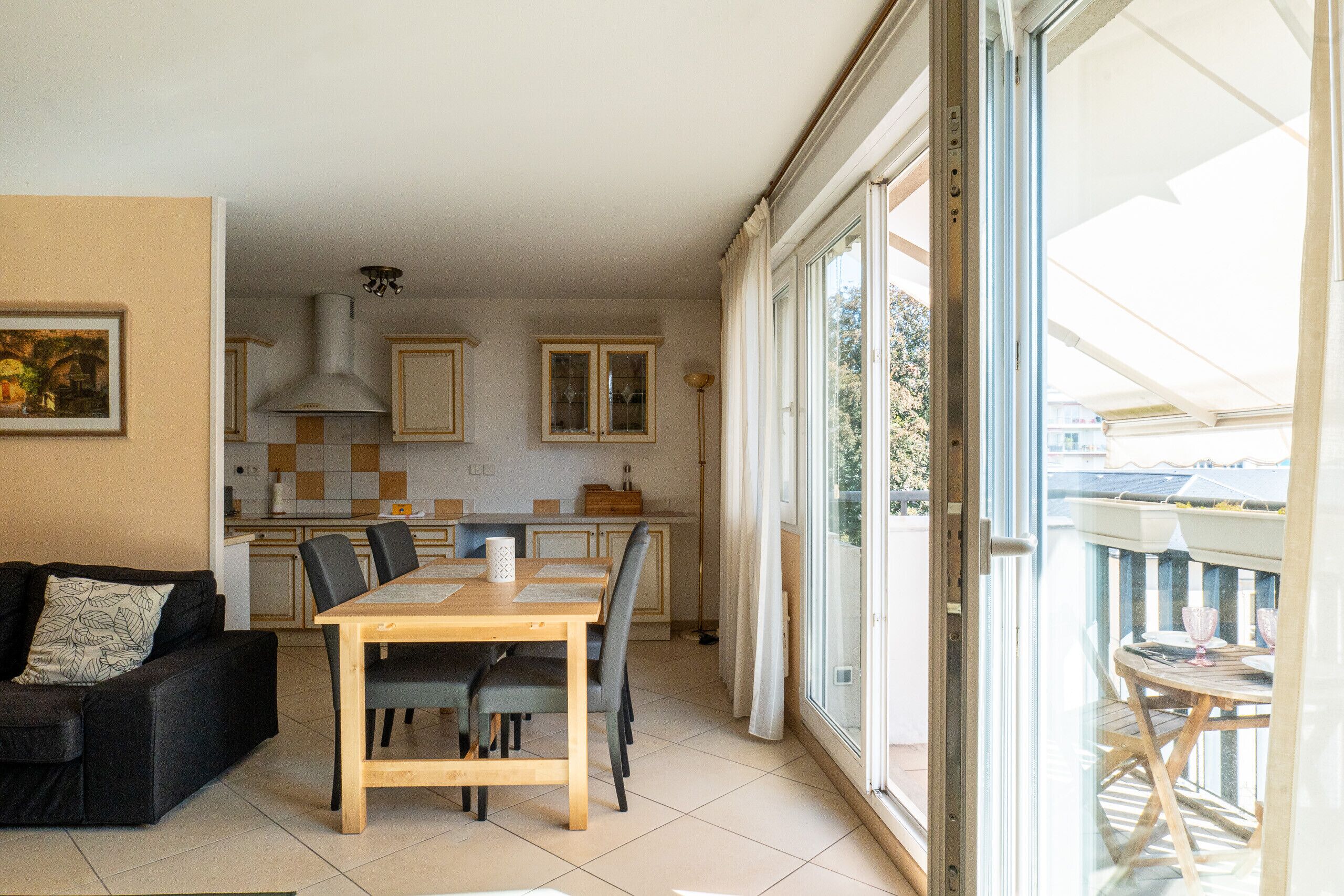 A compact living space with a dining area, kitchenette, and a balcony with outdoor seating.