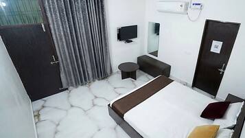A hotel room with a bed, a small round table, a sofa, a TV, and a mirror.
