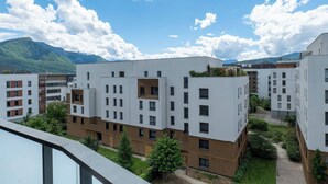 Ein moderner Wohnkomplex mit mehreren Wohngebäuden, einem Dachgarten und einer Bergkulisse.