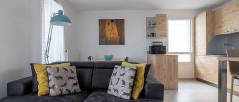 Ein modernes Wohnzimmer mit einer Couch, einem Gemälde und einer Küchenzeile.