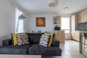 Un saló modern amb un sofà, un quadre i una cuina.
