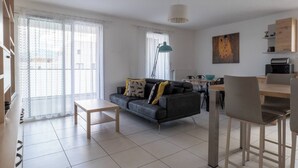 Ein modernes Wohnzimmer mit einer Couch, einem Couchtisch und einem Essbereich mit Stühlen und einem Tisch.