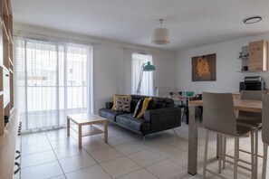 Ein modernes Wohnzimmer mit einer Couch, einem Couchtisch und einem Essbereich mit Stühlen und einem Tisch.