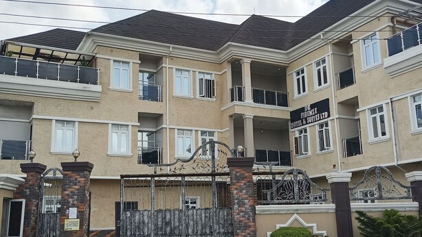 A multi-story hotel with a gated entrance, balconies, and a sign indicating it's a hotel and suites. - De Firenze Suites (Lagos)