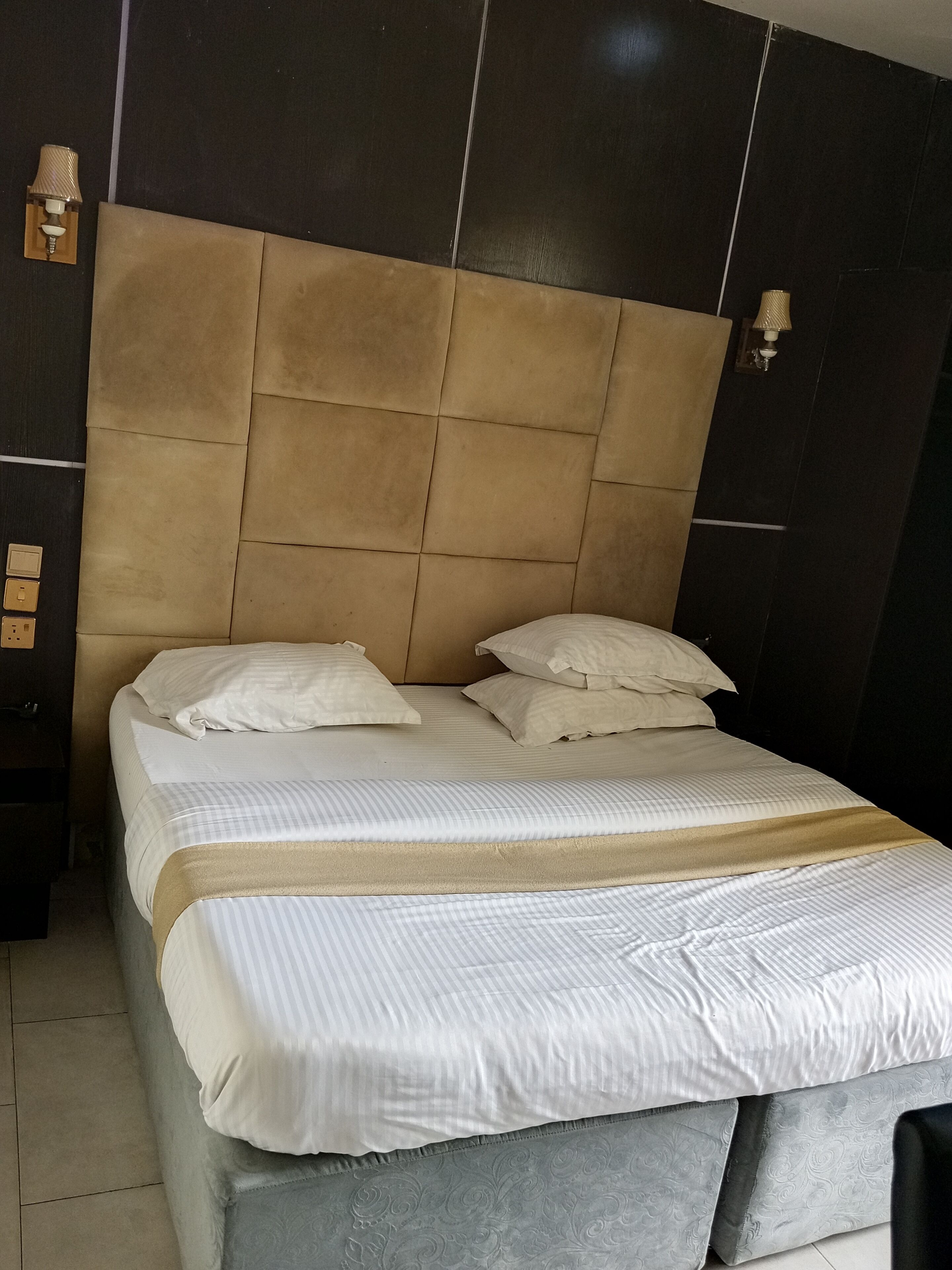 Ein Bett mit Kopfstütze, Kissen und Decke.