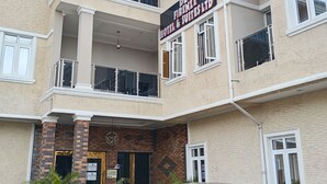 A multi-story hotel with a sign indicating it's a hotel and suites. There is a maroon car parked in front. - De Firenze Suites (Lagos)
