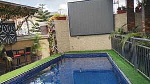 An outdoor swimming pool with a tiled deck, surrounded by a low brick wall and a metal railing. - De Firenze Suites (Lagos)
