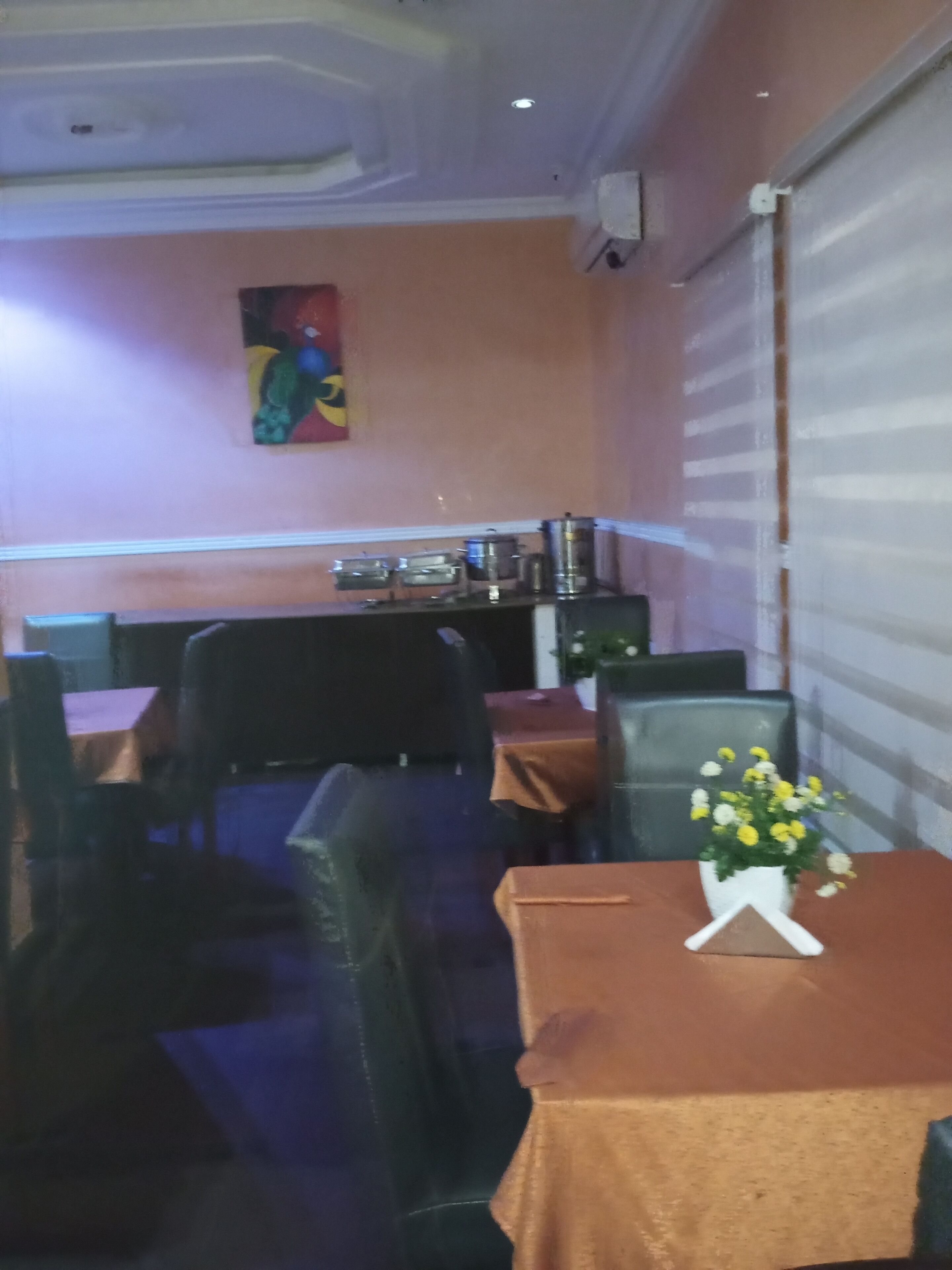Interior de restaurante con cabinas, mesas y un cuadro colgado en la pared.