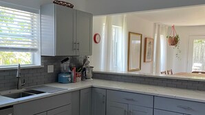 Een moderne keuken met grijze kastjes, een inbouwspoelbak en een raam met zonwering.