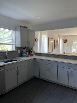 A modern kitchen with grey cabinets, a built-in sink, and a window with blinds. - Lovely modern 3-bedroom house with AC in quiet Houston neighborhood (Houston)