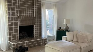 Een moderne woonkamer met een open haard, een bank, een vloerkleed en een lamp.
