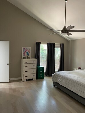 A bedroom with a bed, a dresser, a ceiling fan, and a window with curtains. - Lovely modern 3-bedroom house with AC in quiet Houston neighborhood (Houston)