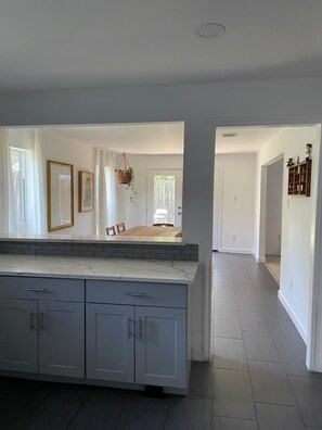 A spacious kitchen with a large island, a dining area with a wooden table, and a hallway leading to another room. - Lovely modern 3-bedroom house with AC in quiet Houston neighborhood (Houston)