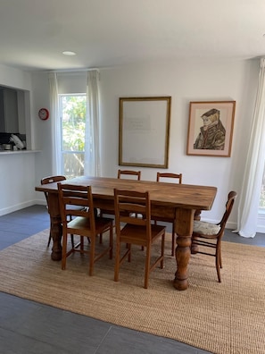 Ein Esszimmer mit Holztisch und -stühlen, einem gerahmten Bild an der Wand und einer Uhr.