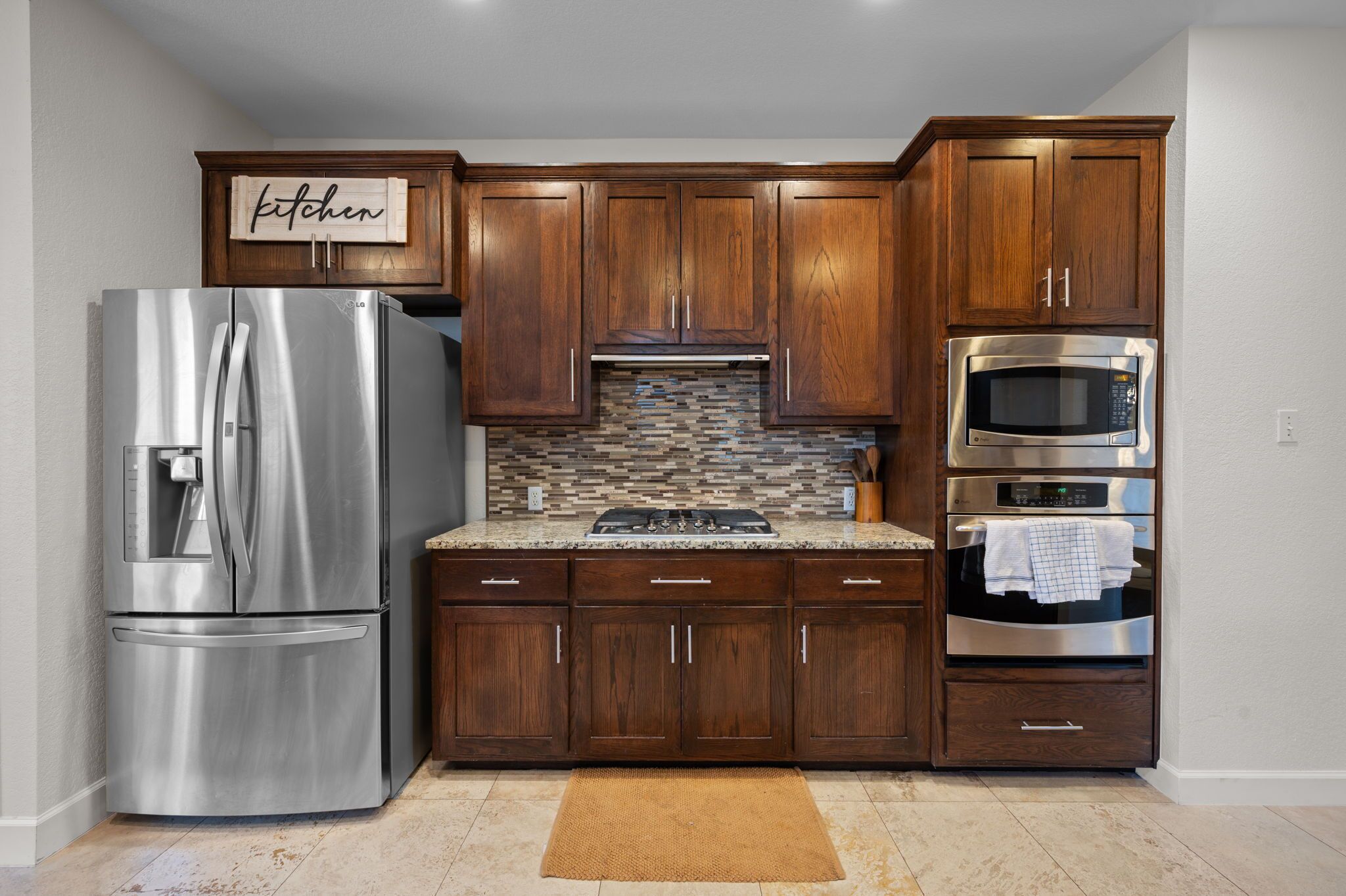Una cocina con armarios de madera, electrodomésticos de acero inoxidable y un salpicadero de azulejos.