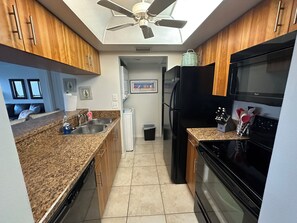 A modern kitchen with granite countertops, stainless steel appliances, and wooden cabinets. - Spacious two bedroom condo across the street from Siesta Key Beach (Sarasota)