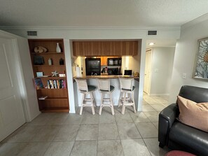 A compact living space with a kitchenette, a bookshelf, and a seating area with a leather couch. - Spacious two bedroom condo across the street from Siesta Key Beach (Sarasota)