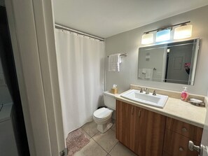 A bathroom with a toilet, sink, mirror, and shower curtain. - Spacious two bedroom condo across the street from Siesta Key Beach (Sarasota)
