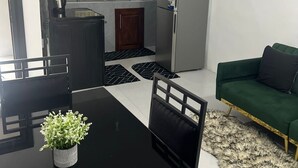 Ett kompakt bostadsutrymme med ett litet kök, en matplats och en soffa.