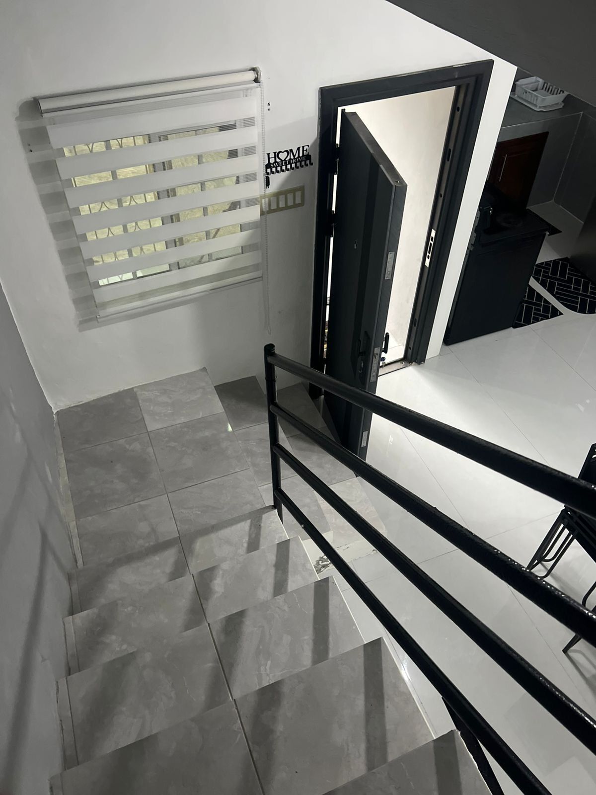 A staircase with a metal railing, a door, and a window with blinds.