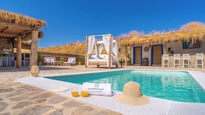 A pool area with a bed, lounge chairs, and a sign for ruraldays. - Amanecer Los Naranjos Ronda by Ruralidays (Málaga)