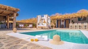 A pool area with a bed, lounge chairs, and a sign for ruraldays. - Amanecer Los Naranjos Ronda by Ruralidays (Málaga)