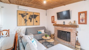 A living room with a sofa, a TV, a fireplace, and a world map artwork. - Amanecer Los Naranjos Ronda by Ruralidays (Málaga)