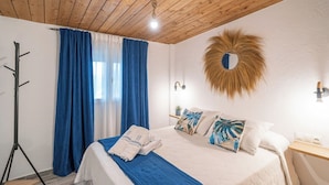 A hotel room with a bed, a nightstand, a mirror, and a coat rack. - Amanecer Los Naranjos Ronda by Ruralidays (Málaga)