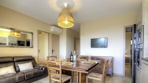 A dining area with a wooden table, chairs, and a hanging light fixture. - Alba - Porto Vecchio (PORTO VECCHIO)