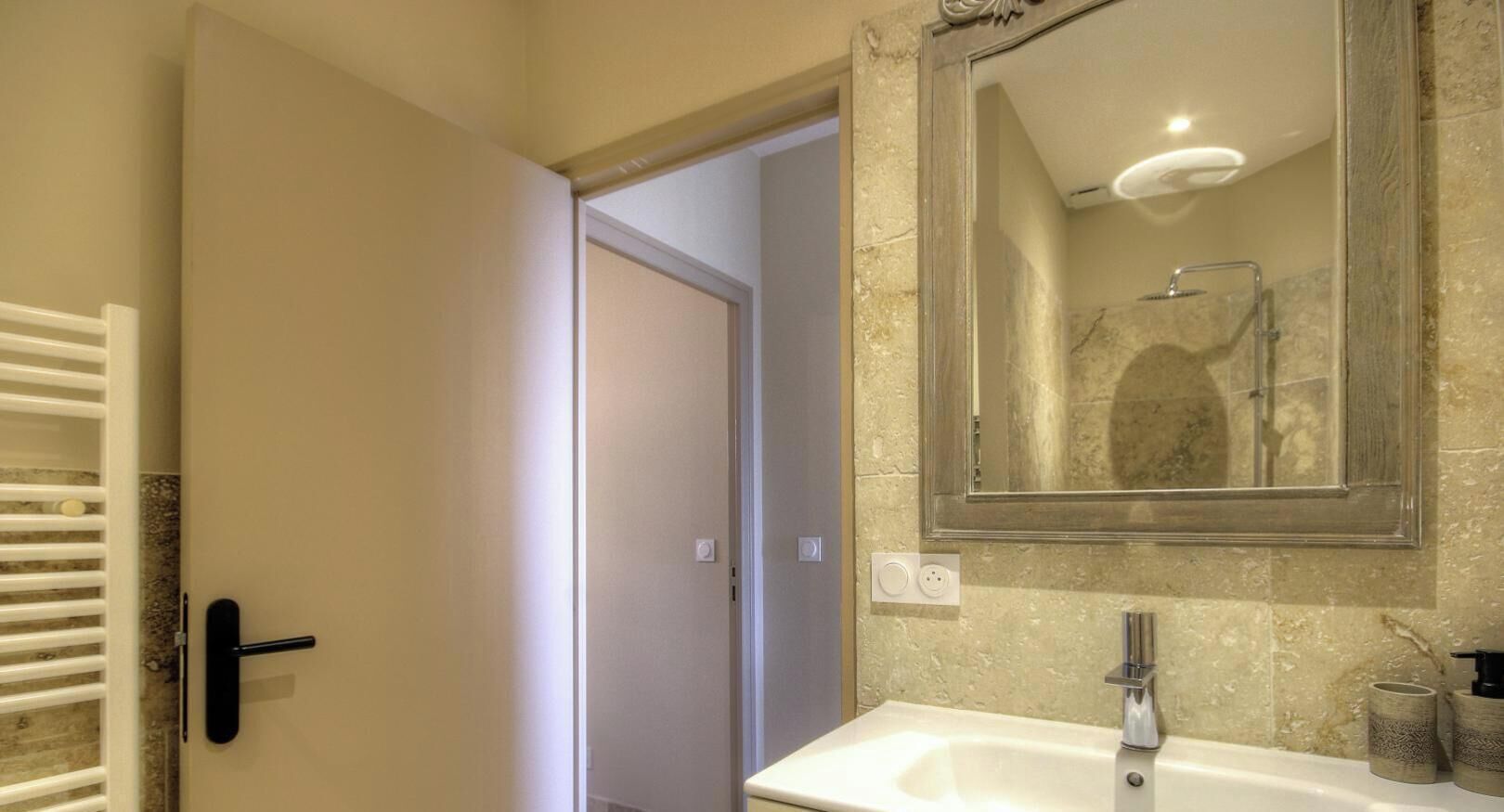 Un baño con lavamanos blanco, espejo y ducha.