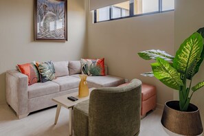 A modern living room with a sofa, a coffee table, a chair, and a large potted plant. - Casa Maguey: A Vibrant Mexican-Inspired Stay (Cartagena de Indias)