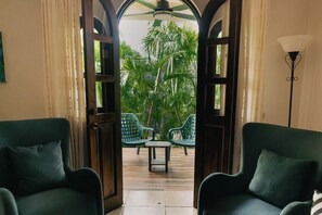 A room with two green chairs, a small table, and a view of a tropical garden through an open doorway. - Peaceful 2-bedroom Villa with AC in beautiful Tamarindo
Steps from the Pool (Tamarindo)