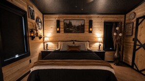 Un dormitorio con una cama grande, paredes de madera, dos lámparas de noche, un cuadro y un reloj en la pared.