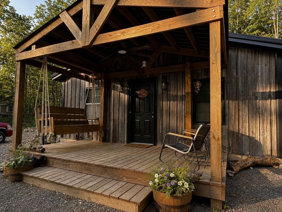 A rustic wooden cabin with a porch, a bench, and a door.