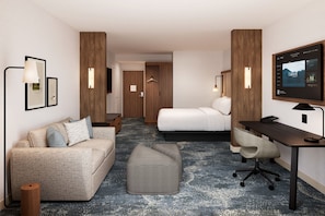 Une chambre d’hôtel équipée d’un canapé, d’un lit, d’un bureau, d’une chaise, d’une télévision et d’une petite table.