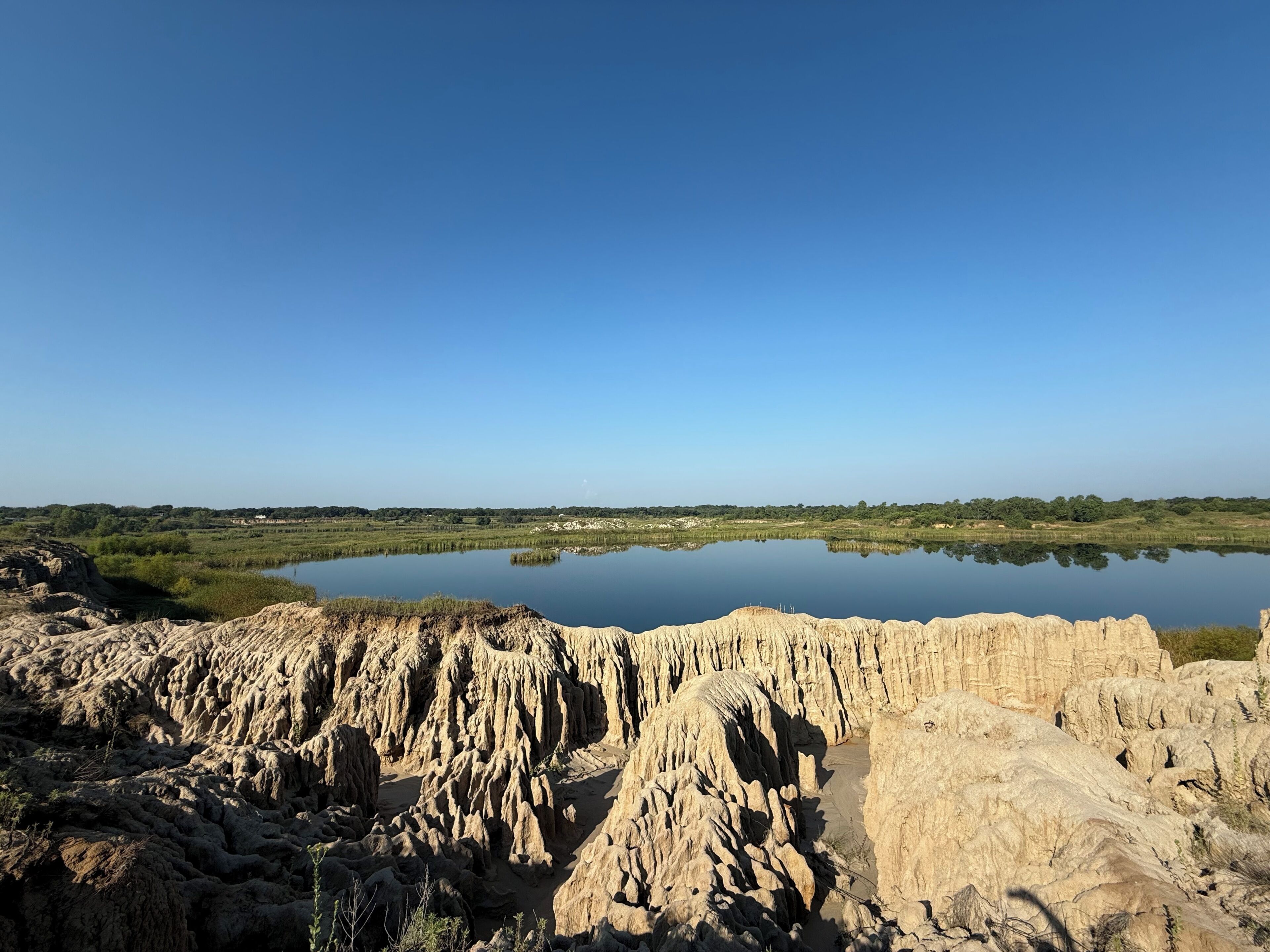 Un paysage naturel comprenant une étendue d’eau, un terrain rocheux et une végétation luxuriante en arri ère-plan.