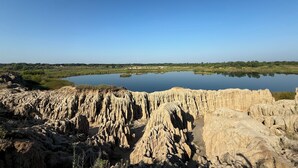 A natural landscape with a body of water, rocky terrain, and distant greenery.