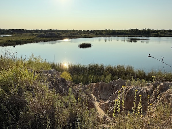 A natural landscape with a calm lake, rocky terrain, and sparse vegetation.