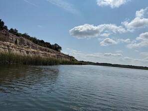 A calm river with a rocky cliff on one side and a clear sky above.